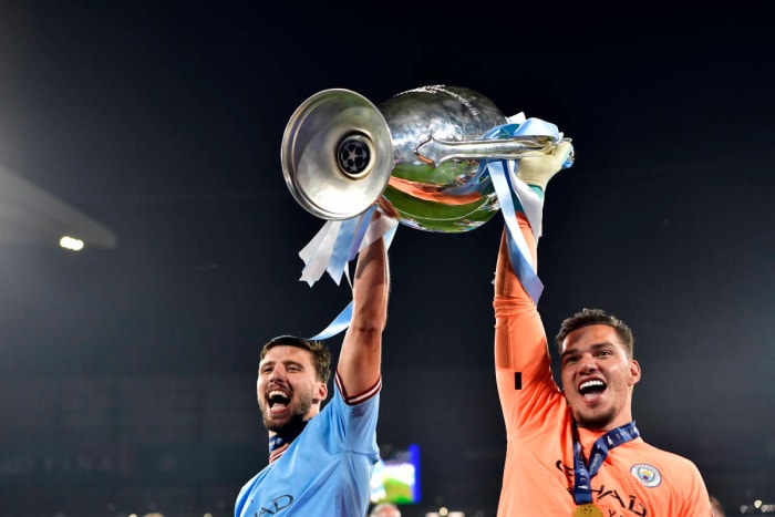 Manchester City teammates Ruben Dias (left) and Ederson pictured lifting the UEFA Champions League trophy together after the 2023 final in Turkey